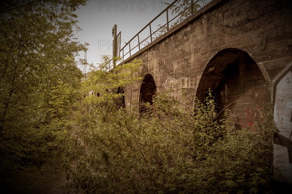 Old overgrown bridge arches in sepia-coloured tones, sign of abandonment, former Rethel railway