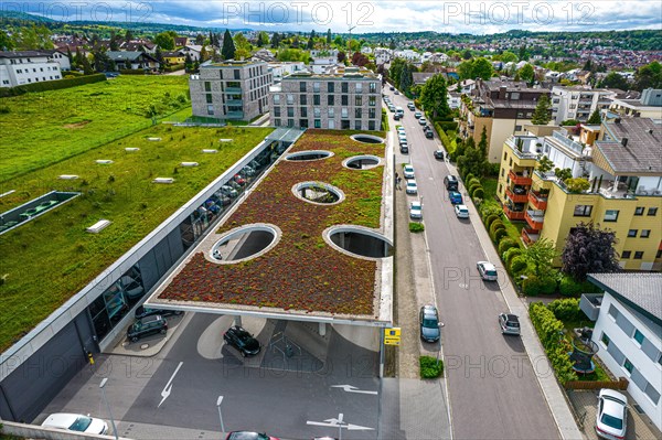 View from above of a building with a green roof, neighbouring meadow and street with cars, Edeka