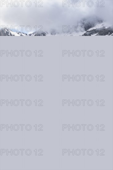 Mountaineer jumping from one rock to the next, cloudy mountain landscape with blooming alpine