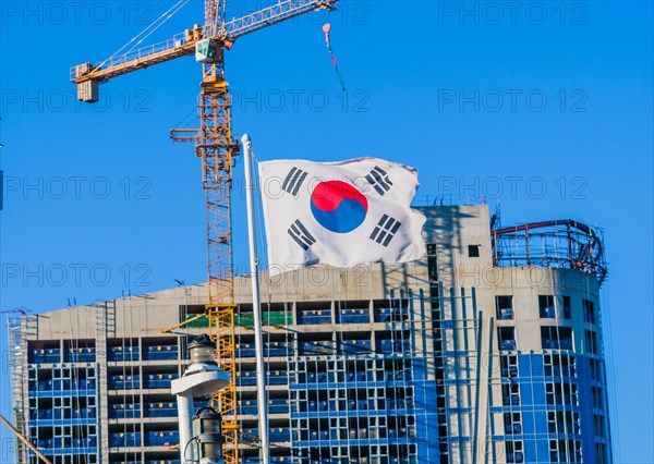 Korean flag on flying from a ship with a construction crane attached to a building under