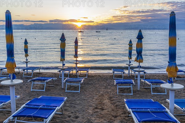 Sun loungers and parasols on Straccolignino beach at sunrise, near Capoliveri, Elba, Tuscan