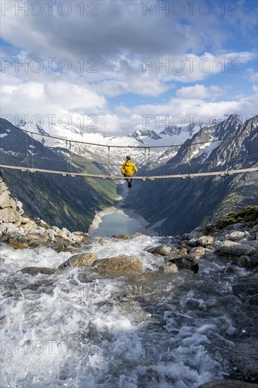Mountaineer sitting on a suspension bridge over a mountain stream Alelebach, picturesque mountain
