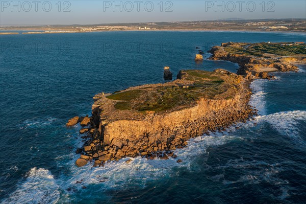 Aerial image of high rocky headland and peninsula. Drone shot of sea blue waves beat and splash in