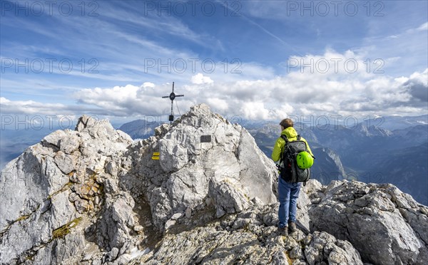 Mountaineer on the rocky summit of the Watzmann Mittelspitze with summit cross, Berchtesgaden
