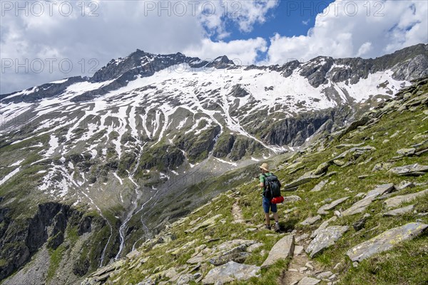 Mountaineer on rocky hiking trail, Berliner Hoehenweg, mountain landscape with snow-covered peak