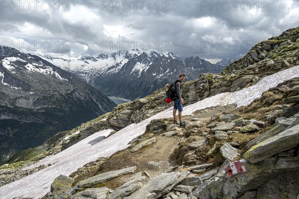 Mountaineer on hiking trail with snow, Berliner Hoehenweg, mountain landscape with glaciated peaks