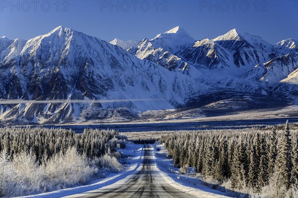 Highway in winter landscape in front of snow-covered mountains, Alaska Highway, Haines Junction,