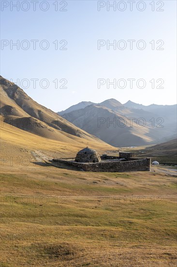 Historic caravanserai Tash Rabat from the 15th century, in the evening light with golden hills,