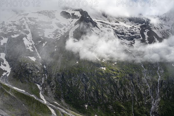 Snow-covered cloudy mountains with Pfitscher ridge and glacier Roetkees, mountain streams as