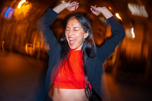 Night photo with flash and motion of an excited woman dancing alone in the city street