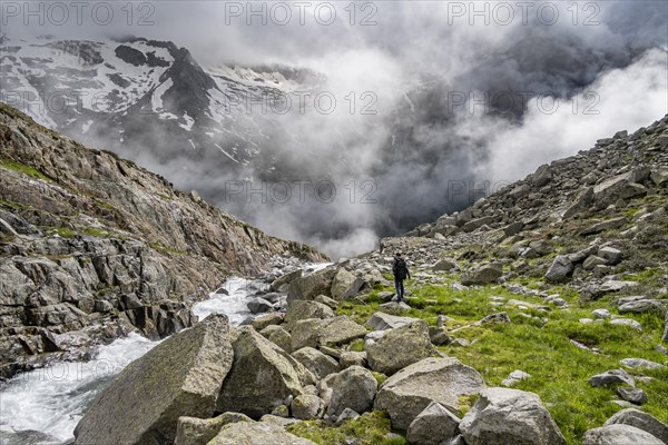 Mountaineer at a mountain stream, Furtschaglbach, cloudy mountains in the background,