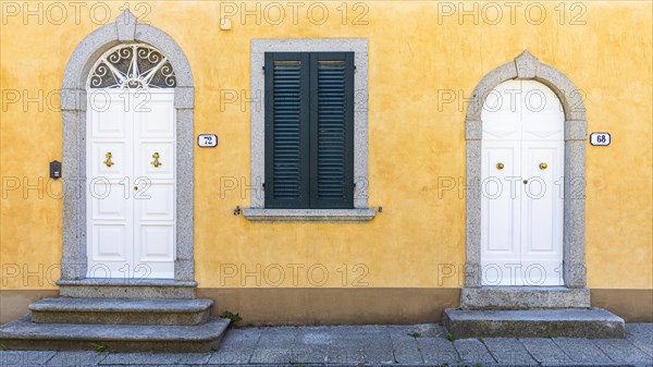 White arched front doors in pastel-coloured house wall, Sant'ilario in Campo, Elba, Tuscan