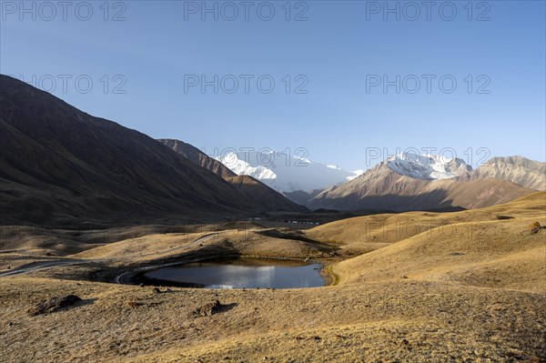 White glaciated and snow-covered mountain peak Pik Lenin at sunrise, mountain landscape with golden