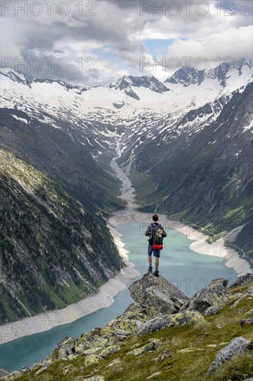 Mountaineer on a rock in front of a mountain panorama, view of Schlegeisspeicher, glaciated rocky