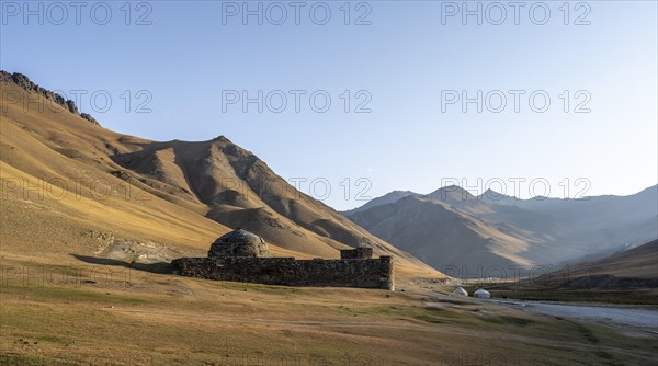 Historic caravanserai Tash Rabat from the 15th century, in the evening light with golden hills and