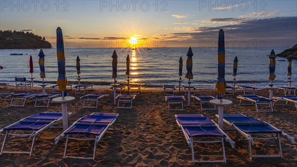Sun loungers and parasols on Straccolignino beach at sunrise, near Capoliveri, Elba, Tuscan