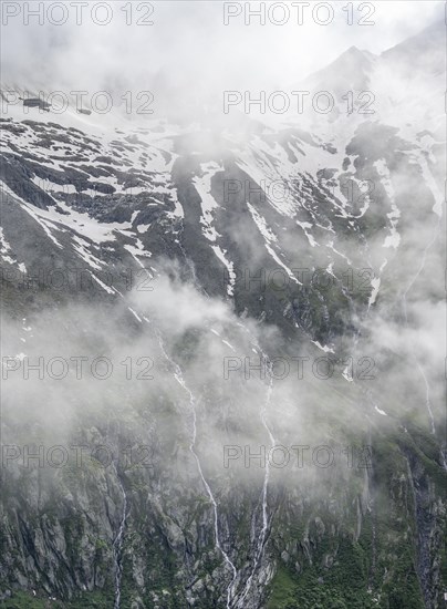 Snow-covered cloudy mountains, mountain streams as waterfalls on a mountain slope, Furtschaglhaus,