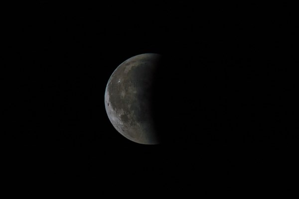 Half moon in the night sky, clearly visible moon craters and grey tint, Haan, North