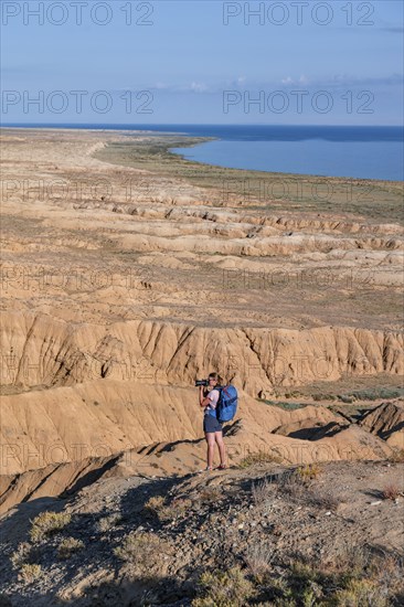 Photographer photographs canyons and eroded hilly landscape, Badlands, Valley of the Forgotten