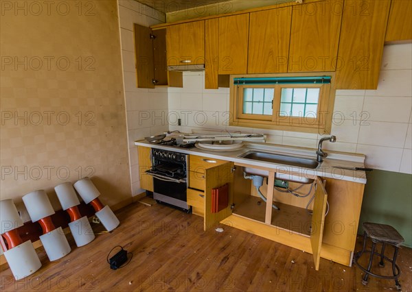 Kitchen area of abandoned house with dirt and electrical fixtures debris on counter top and leaning