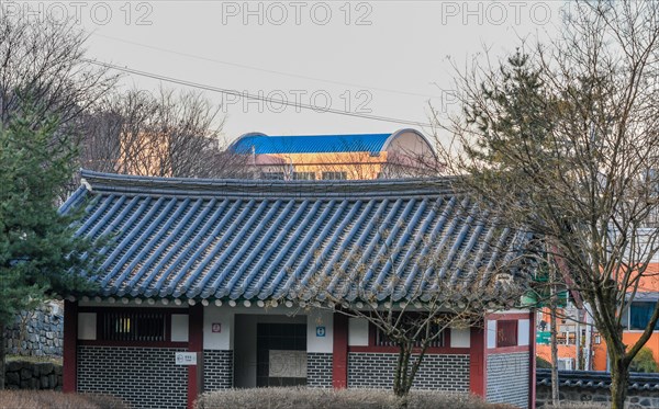 Public restroom in woodland park with a tiled roof surrounded by trees and brushes with a modern