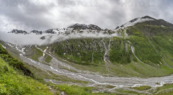 Cloudy valley of Schlegeisgrund with mountain stream, glaciated mountain peaks Hoher Weiszint and