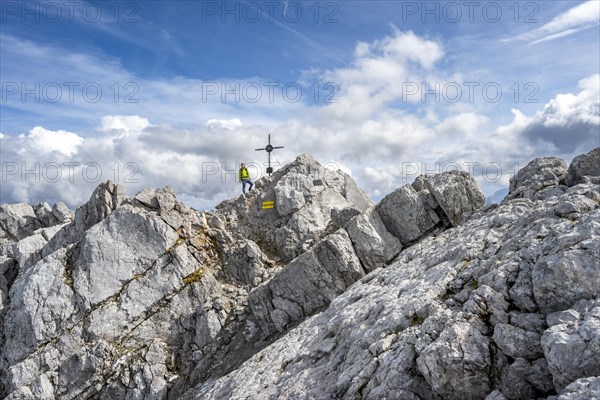 Mountaineer on the rocky summit of the Watzmann Mittelspitze with summit cross, Watzmann crossing,