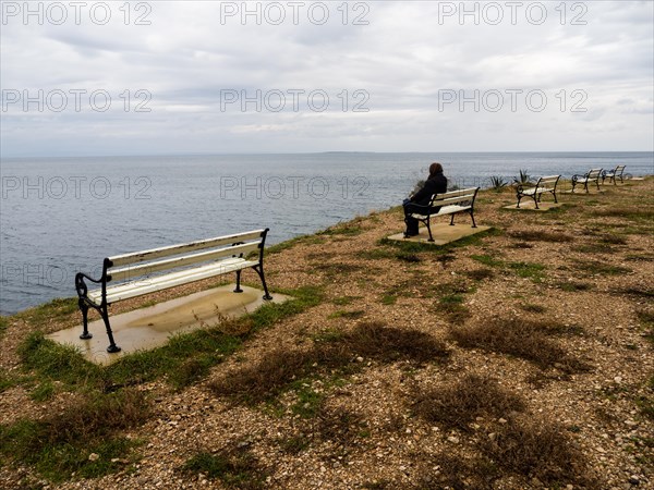 Tourist sitting on a bench and looking out to sea, near Veli Losinj, Kvarner Bay, Croatia, Europe