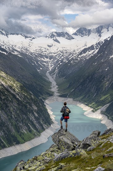Mountaineer on a rock in front of a mountain panorama, view of Schlegeisspeicher, glaciated rocky