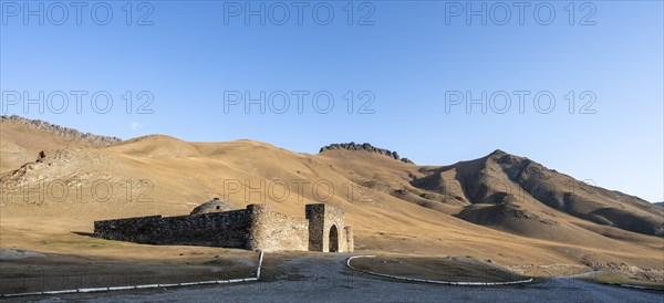 Historic caravanserai Tash Rabat from the 15th century, in the evening light with golden hills,