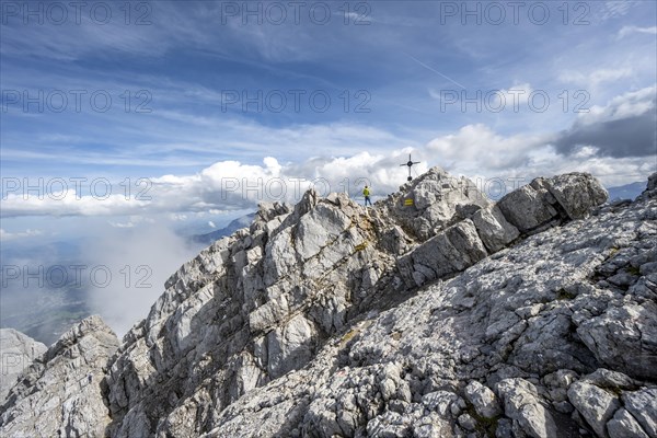 Mountaineer on the rocky summit of the Watzmann Mittelspitze with summit cross, Watzmann crossing,