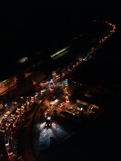 Night view of an illuminated road full of tractors and people, farmers protest, Black Forest, Bad