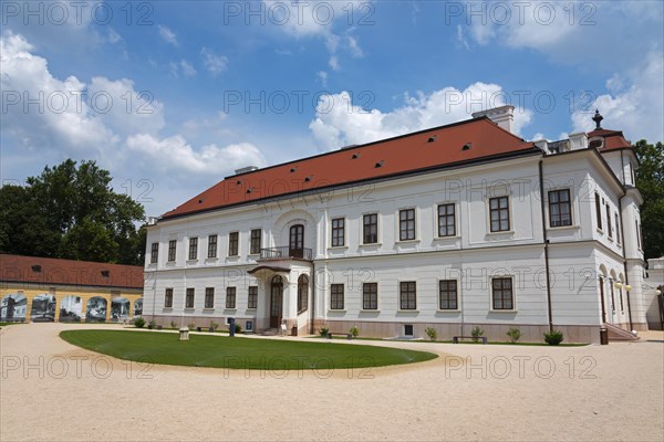 Baroque castle with a red roof and white facade surrounded by a well-tended garden, Esterhazy