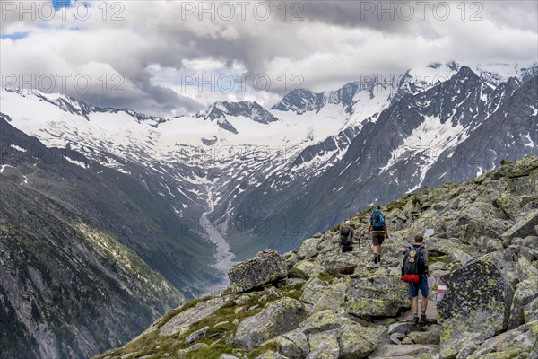 Mountaineer on hiking trail, view of glaciated rocky mountain peaks Hoher Weisszint and Hochfeiler