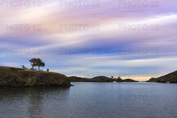 Couple enjoying a picturesque sunset in winter, bay on the Cap de Creus peninsula, Portlligat, Port