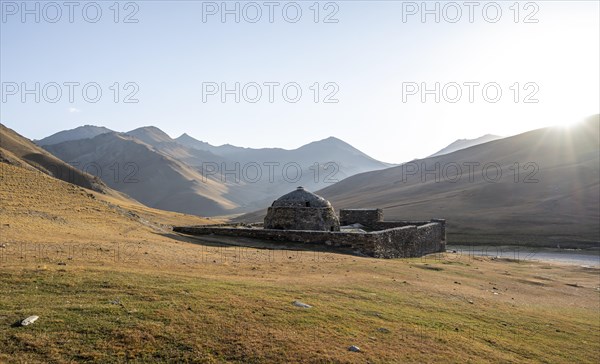 Historic caravanserai Tash Rabat from the 15th century, in the evening light with golden hills,