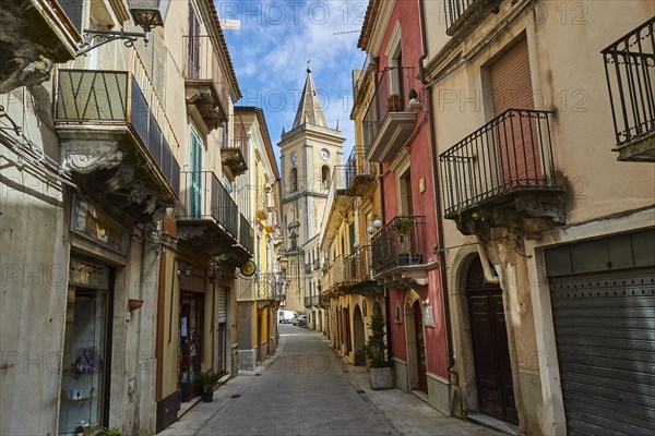 A narrow alley with colourful houses and a church tower at the end, Novara di Sicilia, Sicily,