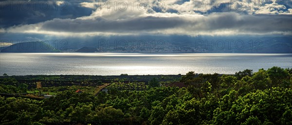 View of the island of Faial and the town of Horta with sun rays breaking through the clouds, Horta,