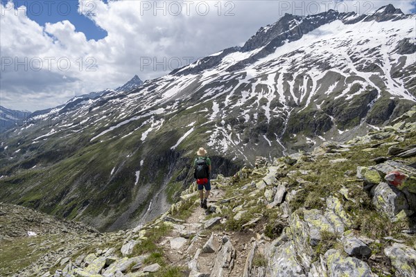 Mountaineer on rocky hiking trail, Berliner Hoehenweg, mountain landscape with snow-covered peak