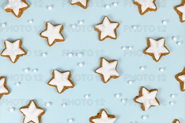 Top view of German star shaped glazed cinnamon Christmas cookies called 'Zimtsterne' on light blue