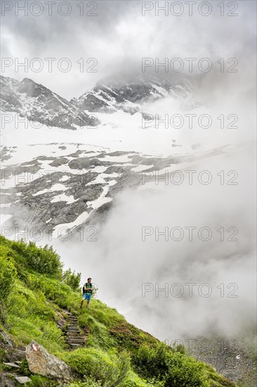 Mountaineers on a hiking trail, Schlegeiskees glacier in the background, cloudy and atmospheric