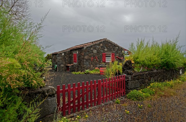 Stone house with red shutters and door and a red fence in a rural area, North Coast, Santa Luzia,