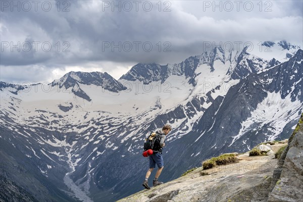Mountaineer on hiking trail, view of glaciated rocky mountain peaks Hoher Weisszint and Hochfeiler