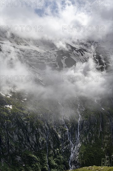 Snow-covered cloudy mountains with summit Hochsteller, mountain streams as waterfalls on a