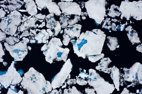 Aerial view over sea ice, drift ice, ice floes with melt ponds containing freshwater in the Arctic
