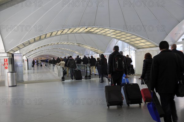 Passengers pulling luggage bags along a bright corridor, Atocha railway station, Madrid, Spain,