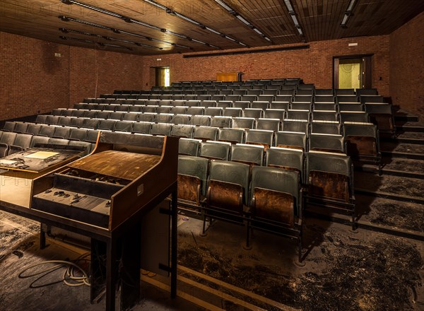 A dark lecture theatre with heavily worn seats and an abandoned lectern, Biotech, abandoned