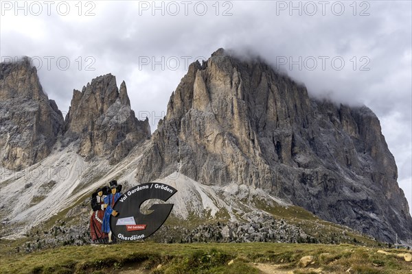 Traditional traditional costume couple advertising sign on the Sella Pass, behind Sassolungo, South