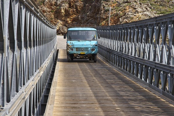 A blue lorry drives over a bridge in mountainous surroundings, Aradena Gorge, Aradena, Sfakia,