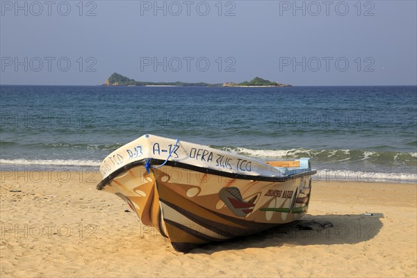 Boat on tropical beach at Nilavelli, Trincomalee, Sri Lanka, Asia with Pigeon Island in background,